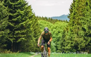 Gravelbiker tritt im Wiegetritt den Berg hinauf