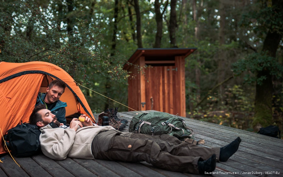 Zwei Wanderer entspannen sich auf einer Trekkingplattform.