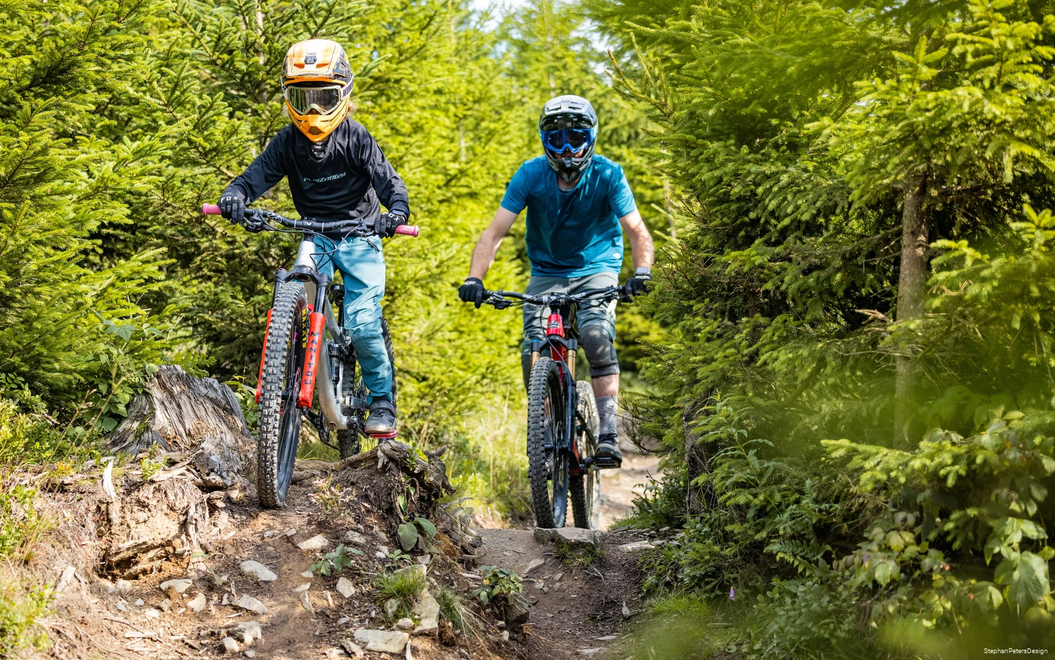 Ein Vater fährt mit seinem Kind einen Bikepark Trail runter