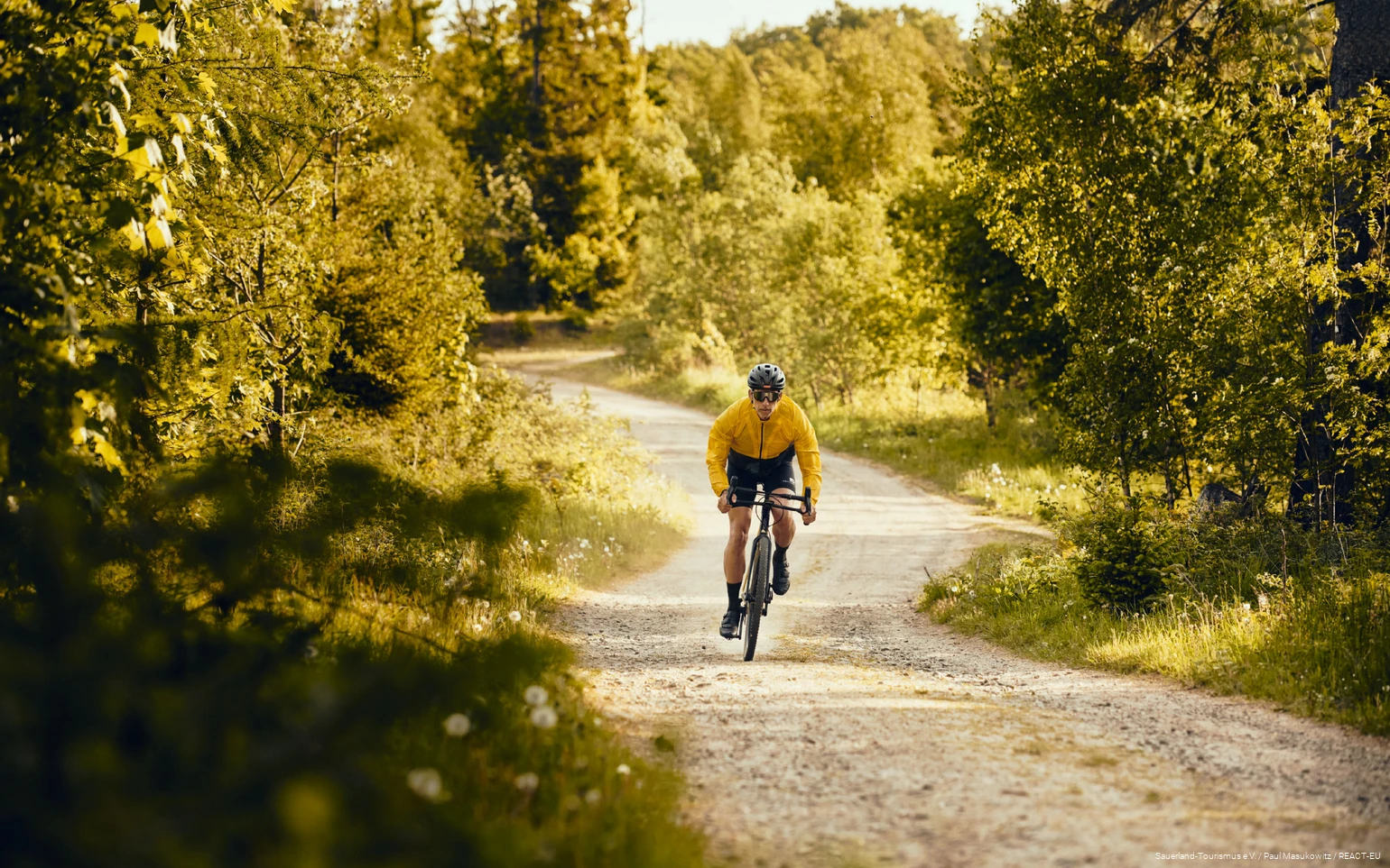 Gravelbiker fährt sehr schnell eine Schotterstraße entlang.