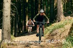 2 Mountainbikerinnen fahren Wurzelpfad im Wald herunter